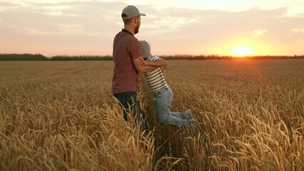 Father farmer and child son playing in wheat field. Child son runs to dad father spins boy in wheat field. Farmer father little son, teamwork in wheat field. Family business. Dad farmer child teamwork © Victoriia