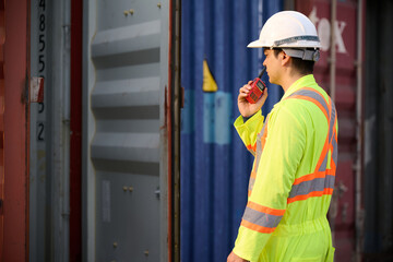 Back view worker or engineer using walkie talkie and talking about work in containers warehouse storage