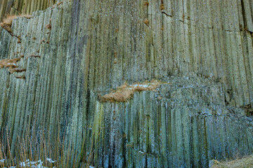 Basalt columns in nature: vertical rock formations with moss and snow