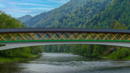 The pedestrian and bicycle bridge known as the “Broken Bridge” spanning the Dunajec River in the picturesque Pieniny Mountains, close to the town of Kroscienko, Poland.