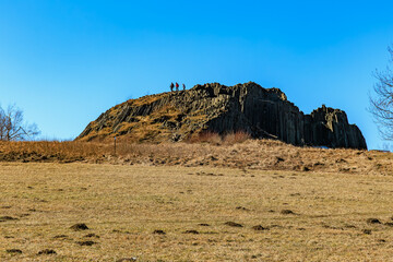 Hikers exploring majestic rock formation with clear blue sky