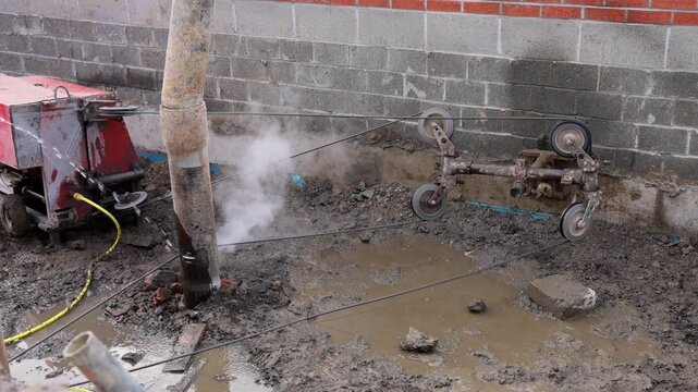 Wire saw guide pulleys in action as spinning and guiding diamond wire cutting structural elements on building site