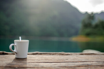 a cup of coffee in a blurry riverside view landscape background in sunshine with narrow depth of field