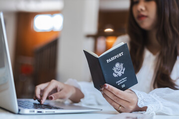Personal travel research moment with woman holding passport and using laptop to plan her next...