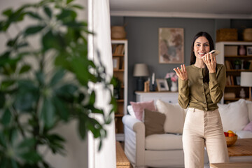 Brunette Woman Smiling While Holding Phone in Naturally Lit Modern Living Room