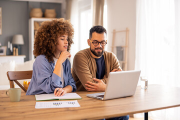Diverse Business Partners Analyze Financial Reports While Working Together At Wooden Desk In Modern Home Office