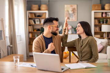Enthusiastic Business Partners Celebrate Success With High Five In Naturally Lit Modern Home Workspace
