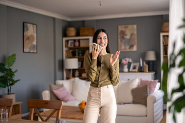 Brunette Woman Smiling While Holding Phone in a Modern Naturally Lit Living Room
