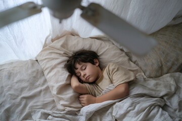 Sleeping soundly in soft light with a gentle fan: A serene childhood moment of peaceful rest and comfort.