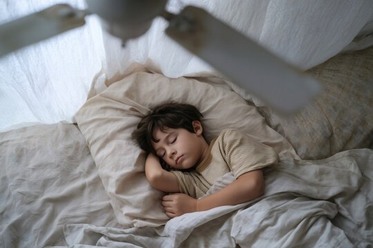 Sleeping soundly in soft light with a gentle fan: A serene childhood moment of peaceful rest and comfort.
