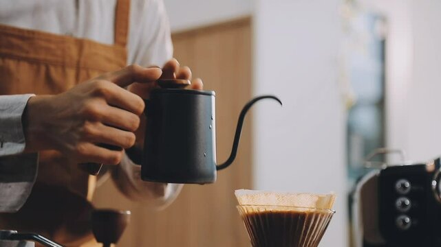 Professional barista preparing coffee using chemex pour over coffee maker and drip kettle. Young woman making coffee. Alternative ways of brewing coffee. Coffee shop concept.
