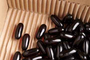 Dark omega 3 capsules in cardboard mailing box close-up. Delivery of medicines concept
