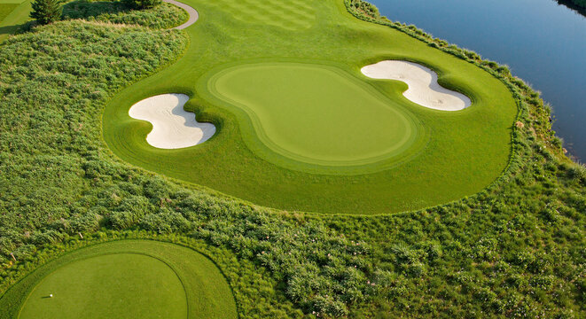 Golf green with sand traps near water for landscape-focused tournament materials and strategy content