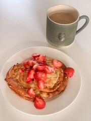 Breakfast apple crumble buns with strawberries and coffee with milk in a green cup with a pine cone on the side, white background