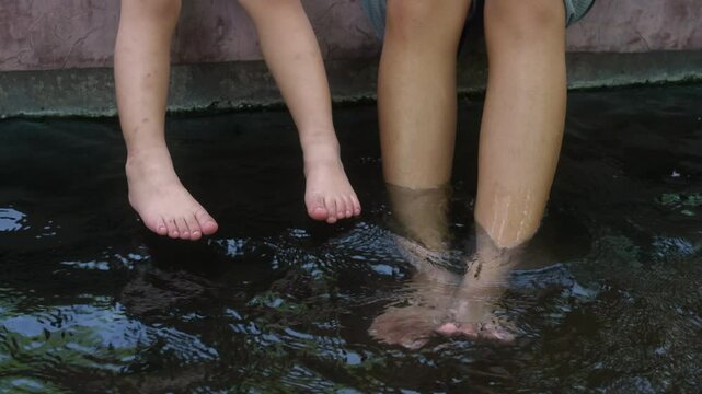 A tender moment unfolds as a young mother and her three year old daughter share the soothing warmth of a hot spring, their legs intertwined, tiny feet splashing alongside hers in joyful unison.
