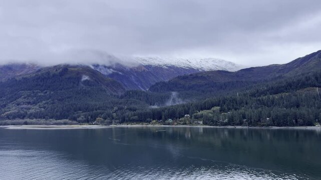 USA, Alaska, Juneau, Thane Road - slowly sailing Gastineau Channel viewing snow covered Mount Robert's Peak from cruise ship on overcast day