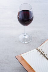Red wine glass and notebook on table
