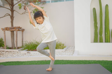 a little girl does yoga lying on a sports mat in the park. a healthy lifestyle is a childish habit 
