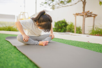 a little girl does yoga lying on a sports mat in the park. a healthy lifestyle is a childish habit 
