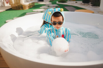Family having fun playing foam in the bathroom. Children hold a handful of foam.