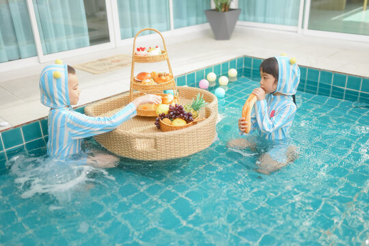 A boy and a girl are having breakfast in the swimming pool.