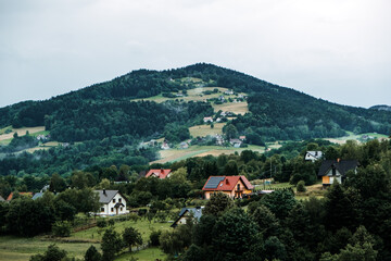 Scenic view of a hillside village with scattered houses among forested and agricultural slopes. Eco-tourism, sustainable tourism, cultural preservation, authentic village experiences...