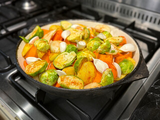 Raw Vegetables: Potatoes, Pumpkin, Carrots, Garlic, and Brussels Sprouts in a Cast Iron Skillet Before Roasting. Vegetable-Based Homemade Food Concept. Handmade Mobile Photo, Selective Focus, Not AI
