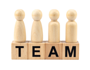 Four wooden figures stand on blocks spelling out the word "TEAM".