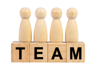 Four wooden figures stand on blocks spelling the word TEAM.
