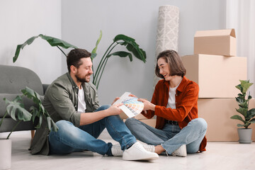 Moving day. Happy couple choosing paint color for their new home