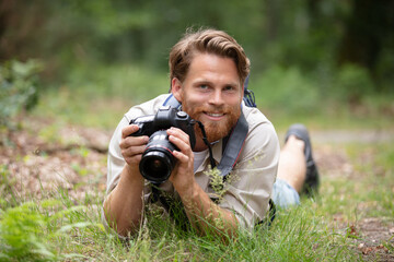 young male photographer laid on grass holding camera