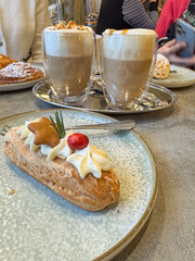 Side view of gingerbread eclair cake and two holiday coffee drinks with cream in the background