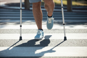 man trying to walk on street with the help crutches