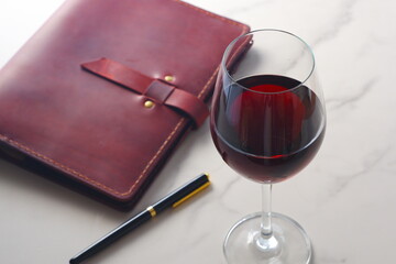 Red wine glass and notebook on table
