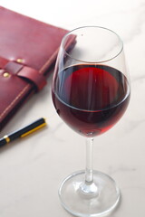 Red wine glass and notebook on table
