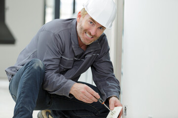 portrait of mature male electrician installing socket