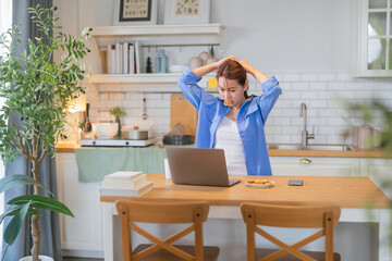A casual relax young woman is looking at a laptop in the kitchen at home Smiling young female...