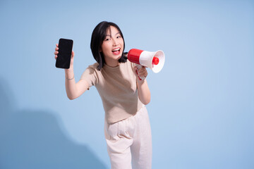Young Asian woman enthusiastically holds a smartphone and megaphone while engaging with an audience...