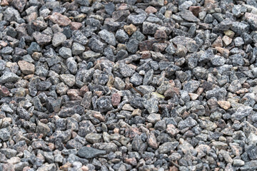 A pile of rocks with a grayish color. The rocks are scattered all over the ground. The image has a rough and rugged appearance