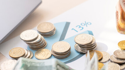 A pile of coins and bills on a table with a pie chart on top. The pie chart shows that 13 of the coins and bills are worth more than