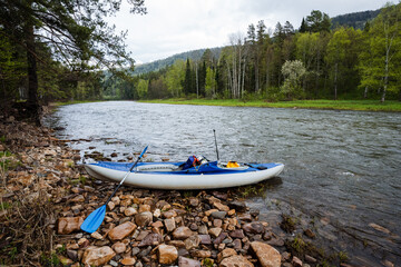 Experience the joy of kayaking on a serene riverbank, beautifully surrounded by lush greenery and stunning, scenic hills that contribute to the peaceful atmosphere of this outdoor adventure