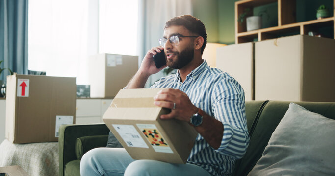 Phone call, cardboard box and man with package in home for mistake with online order with ecommerce. Cellphone, moving and male person on mobile conversation for return of wrong parcel in apartment.