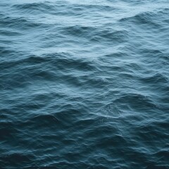 Obraz premium Aerial view of ocean waves lapping and rippling in a serene blue color; nature background of water movement and texture in the sea