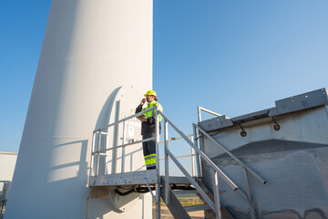 Engineer wearing uniform inspection and survey work in wind turbine farms rotation to generate electricity energy. Maintenance engineer working in wind turbine farm at sunset.