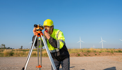 Engineer wearing uniform inspection and survey work in wind turbine farms rotation to generate electricity energy. Maintenance engineer working in wind turbine farm at sunset.
