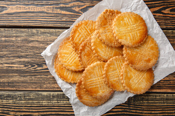 Sable Breton sweet-salty shortbread biscuits closeup on parchment paper on wooden table. Horizontal top view from above