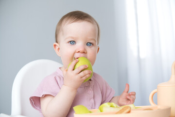 cute baby eating apple sitting in a baby chair. weaning