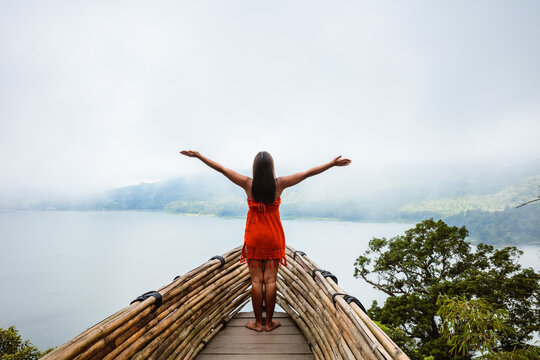 Woman rejoicing on platform over lake, Bali, Indonesia