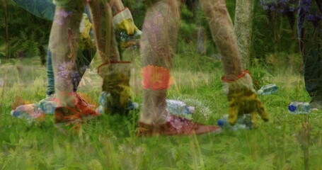 Collecting volunteers gathering plastic bottles in grassy meadow, with gloves and rubber boots