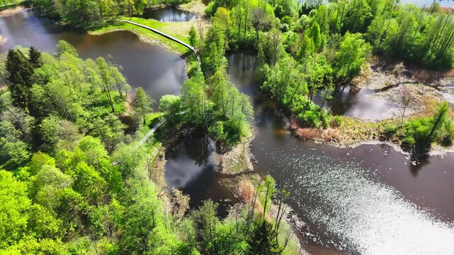 Biržai Regional Park, Lithuania - A Scenic View of Meandering Bridges, Shimmering Karst Lake Waters, and Vibrant Green Foliage - Orbit Drone Shot